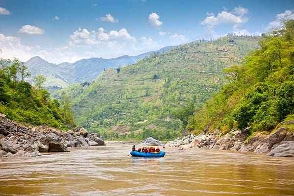 Mountains and people doing rafting on a musky river.